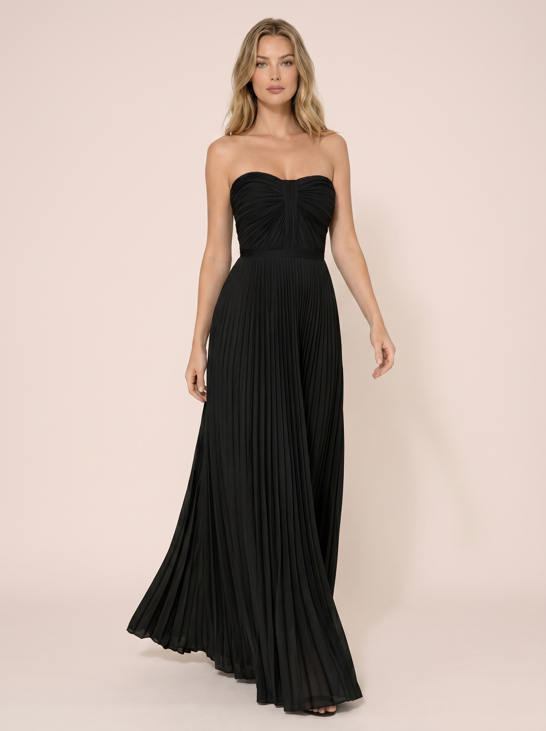 Black strapless pleated maxi dress, full-length view of model walking in a bright studio