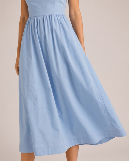 Close-up of blue A-line midi dress waist seam and flowing skirt showing soft fabric texture