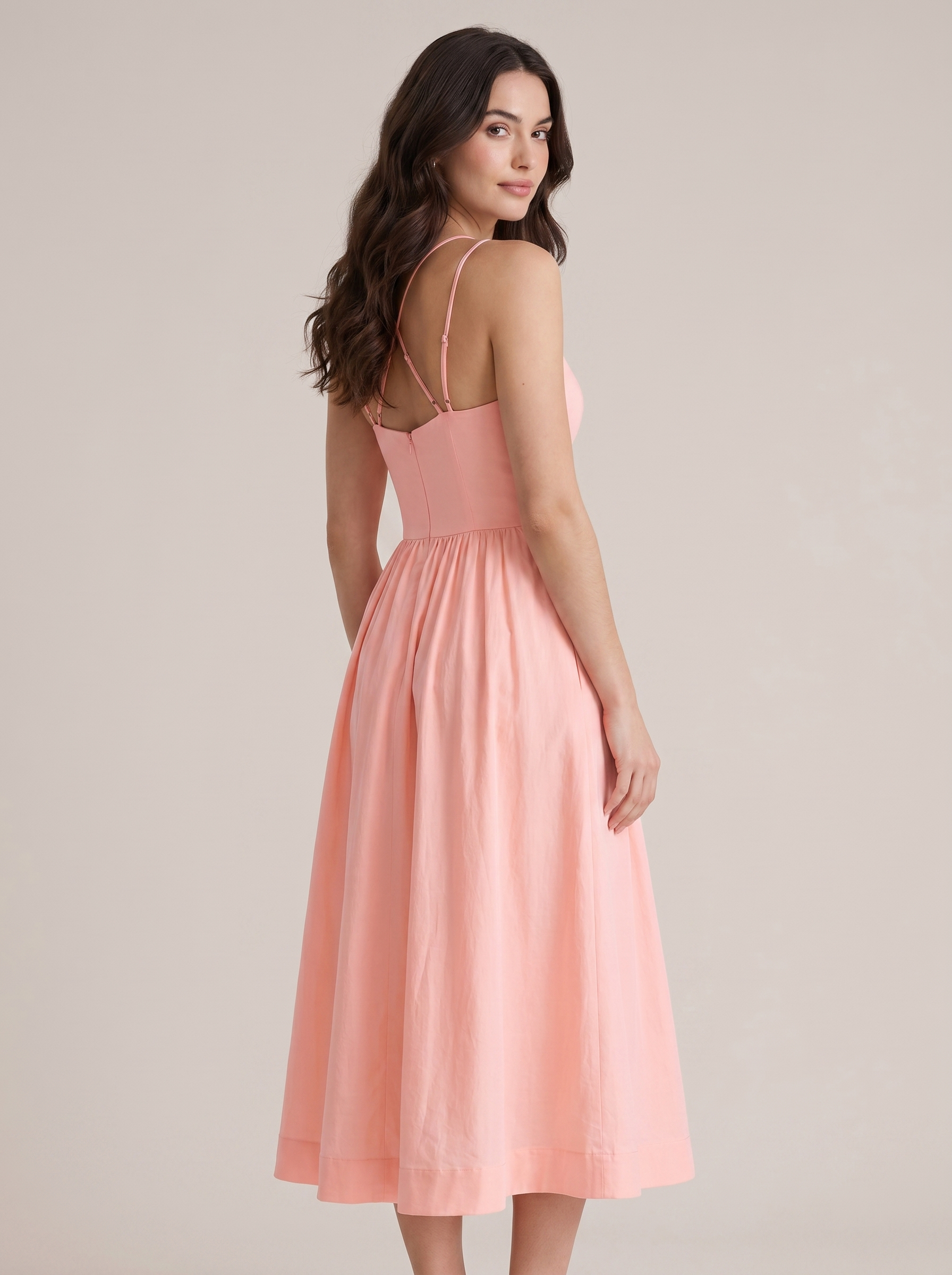 Pink A-line wedding guest midi dress, back view showing strappy bodice and full skirt on model
