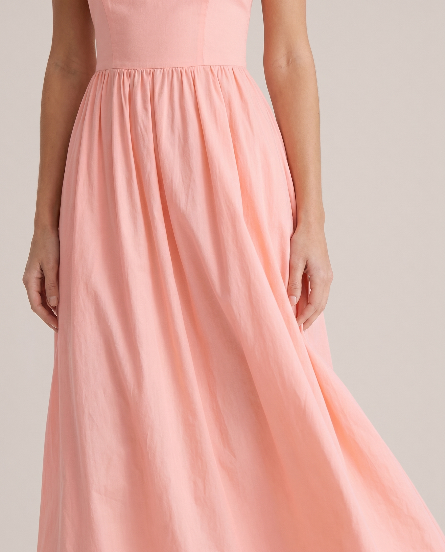 Close-up of pink A-line midi dress waist seam and flowing skirt showing soft fabric texture