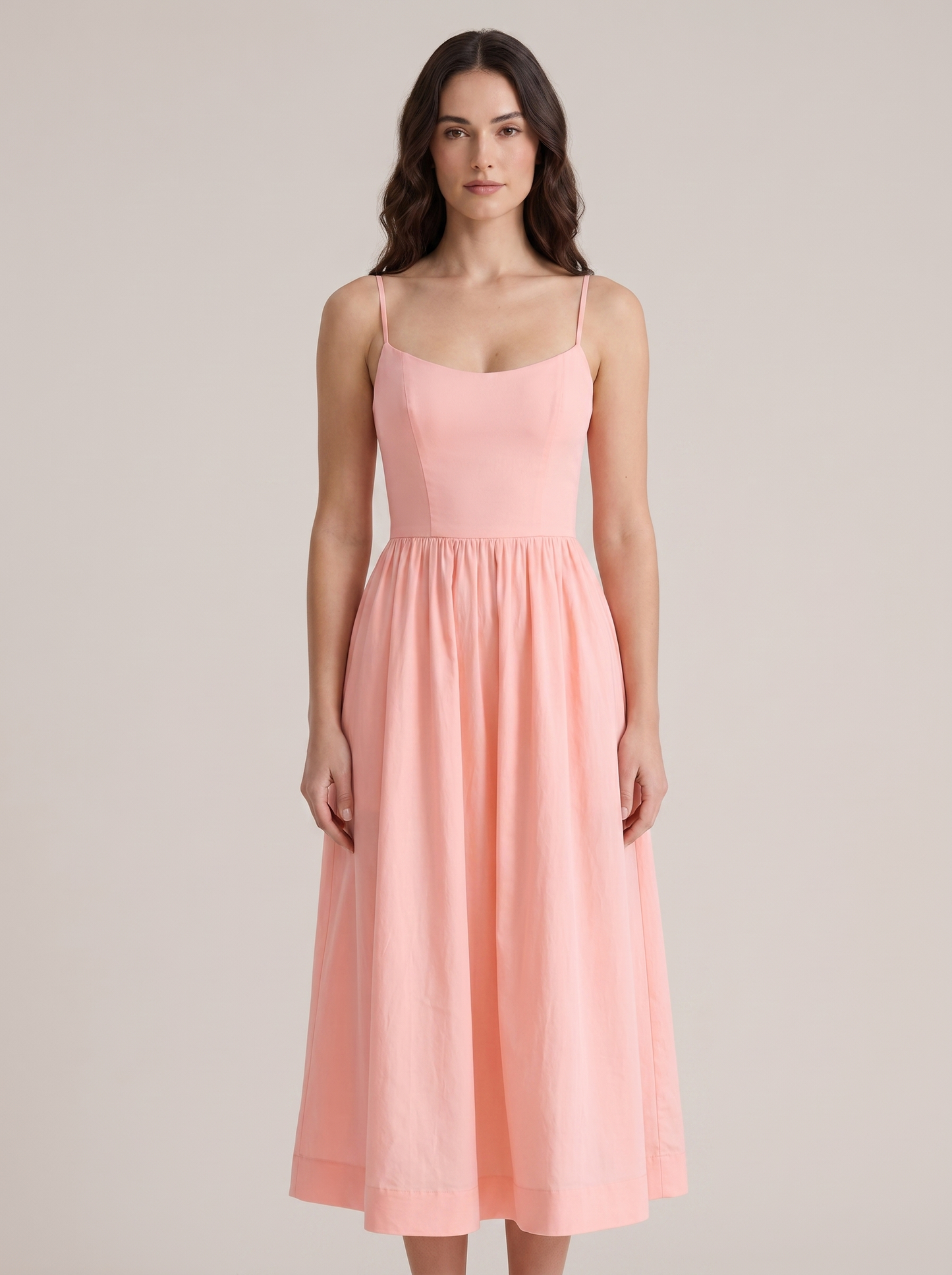 Pink A-line wedding guest midi dress with thin straps and fitted bodice, front view on model