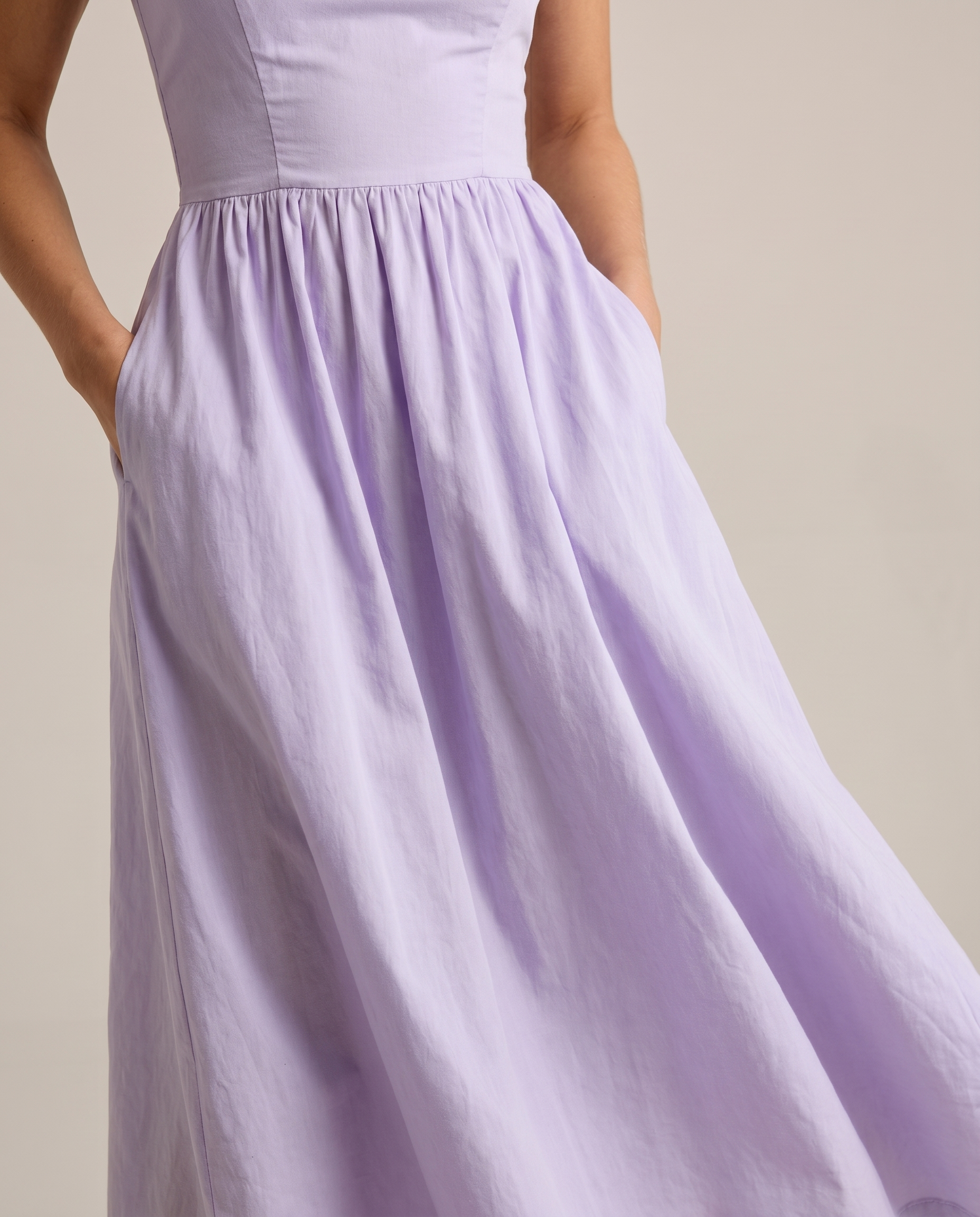 Close-up of purple A-line midi dress waist seam and flowing skirt showing soft fabric texture