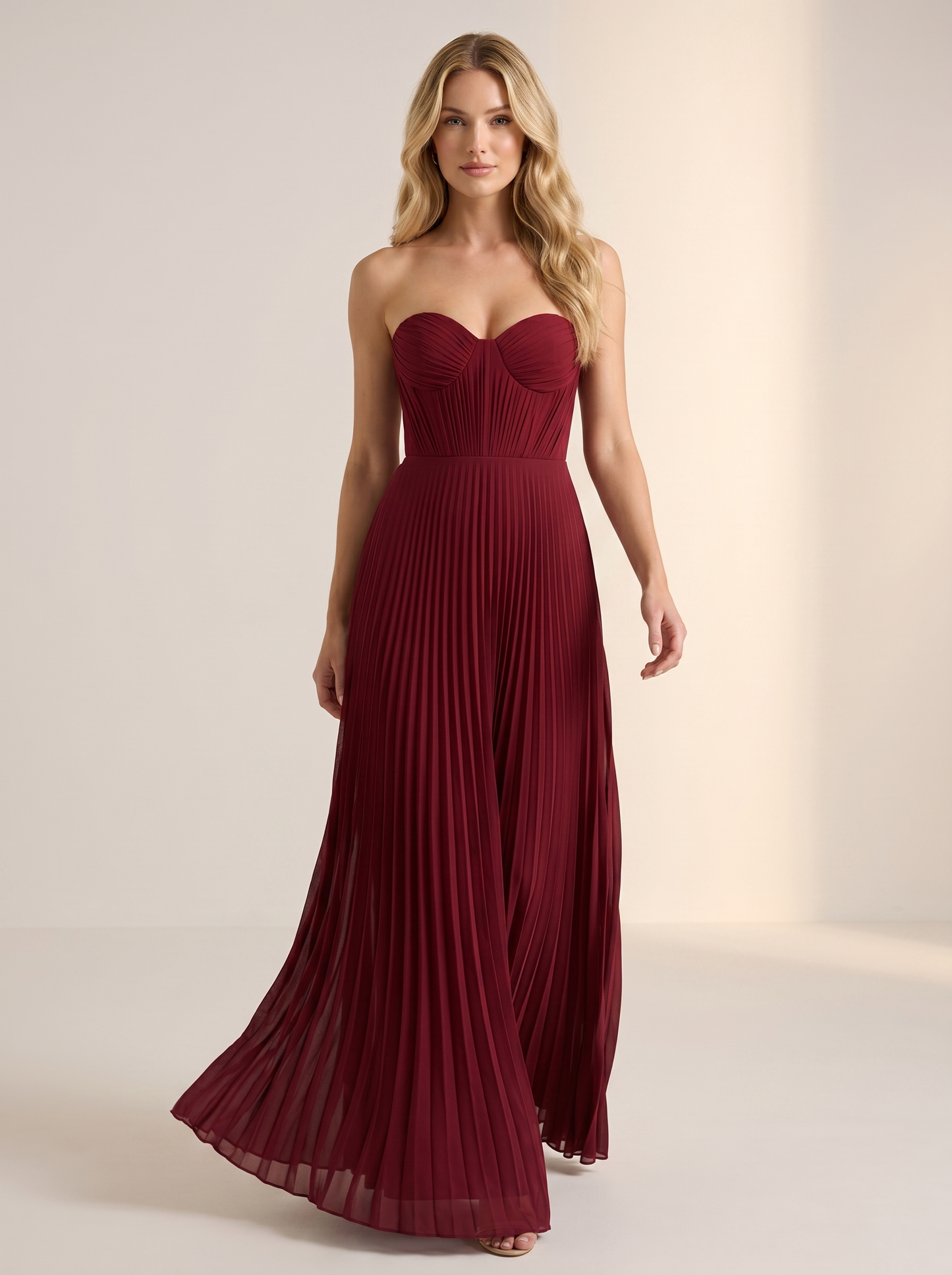 Red strapless pleated maxi dress, full-length view of model walking in a bright studio