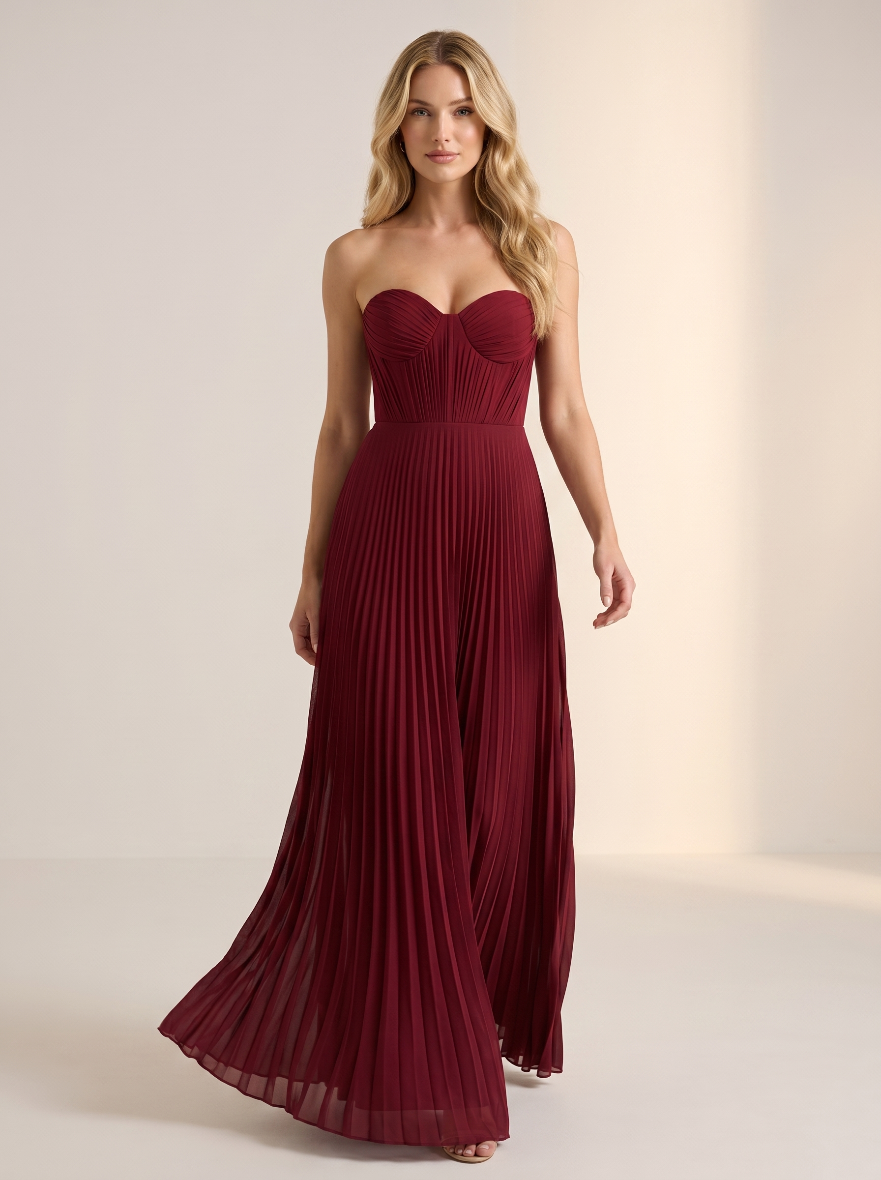 Red strapless pleated maxi dress, full-length view of model walking in a bright studio