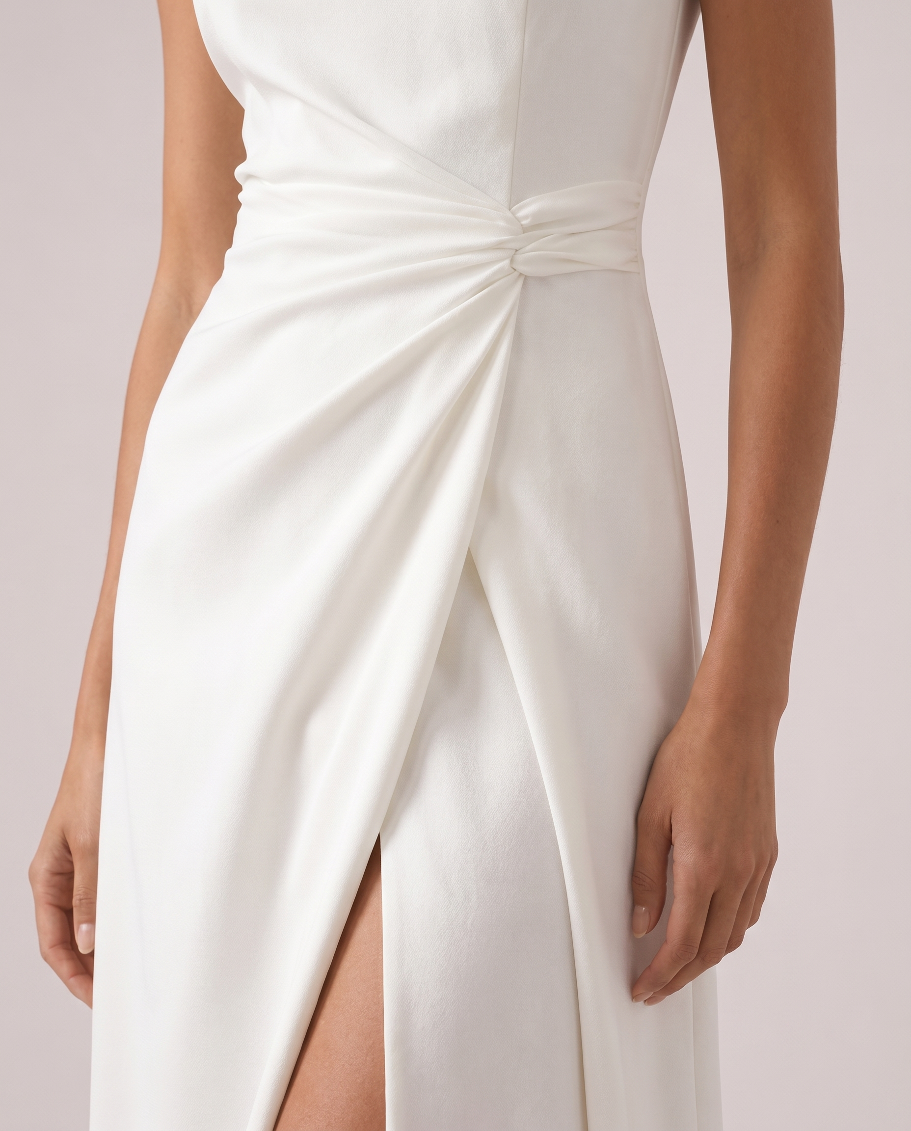 Close-up of white satin maxi dress showing draped waist gathering and high thigh slit detail